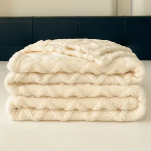 Folded beige fleece blanket with soft texture on a bed