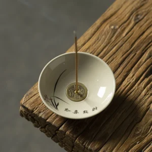 Handcrafted ceramic incense dish with symbolic coin design on rustic wooden surface