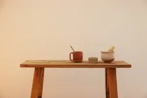 Matcha set with ceramic bowl, bamboo whisk, mug, and green tea on rustic wooden table